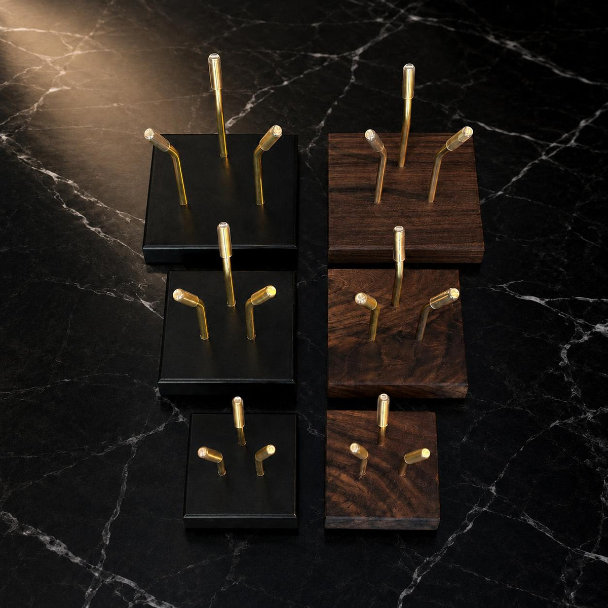 Full range of Sculptural Pedestals in Small, Medium, and Large sizes, shown in Black and Walnut finishes with brass mounting posts, on marble